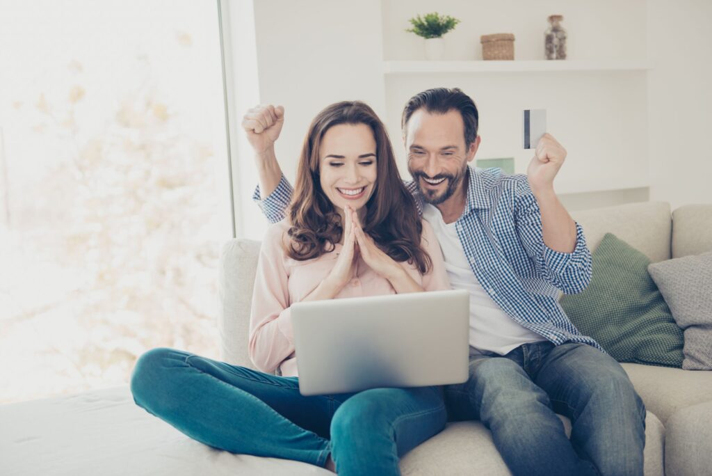 Smiling woman with white hair sitting on a couch in a bright living room