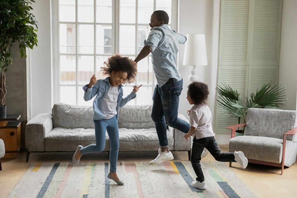 Father and children jumping and playing joyfully at home, feeling happy and energetic