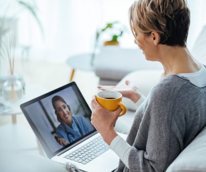 Woman sitting on the sofa while making video call over laptop with her doctor.